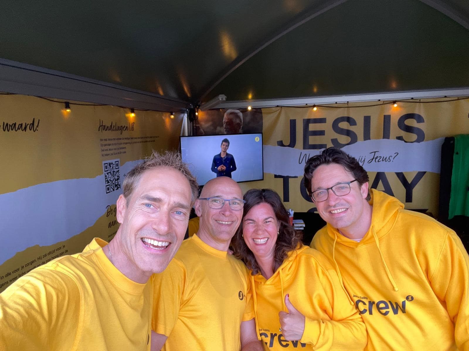 Vier crewleden van JesusToday in gele shirts op een event